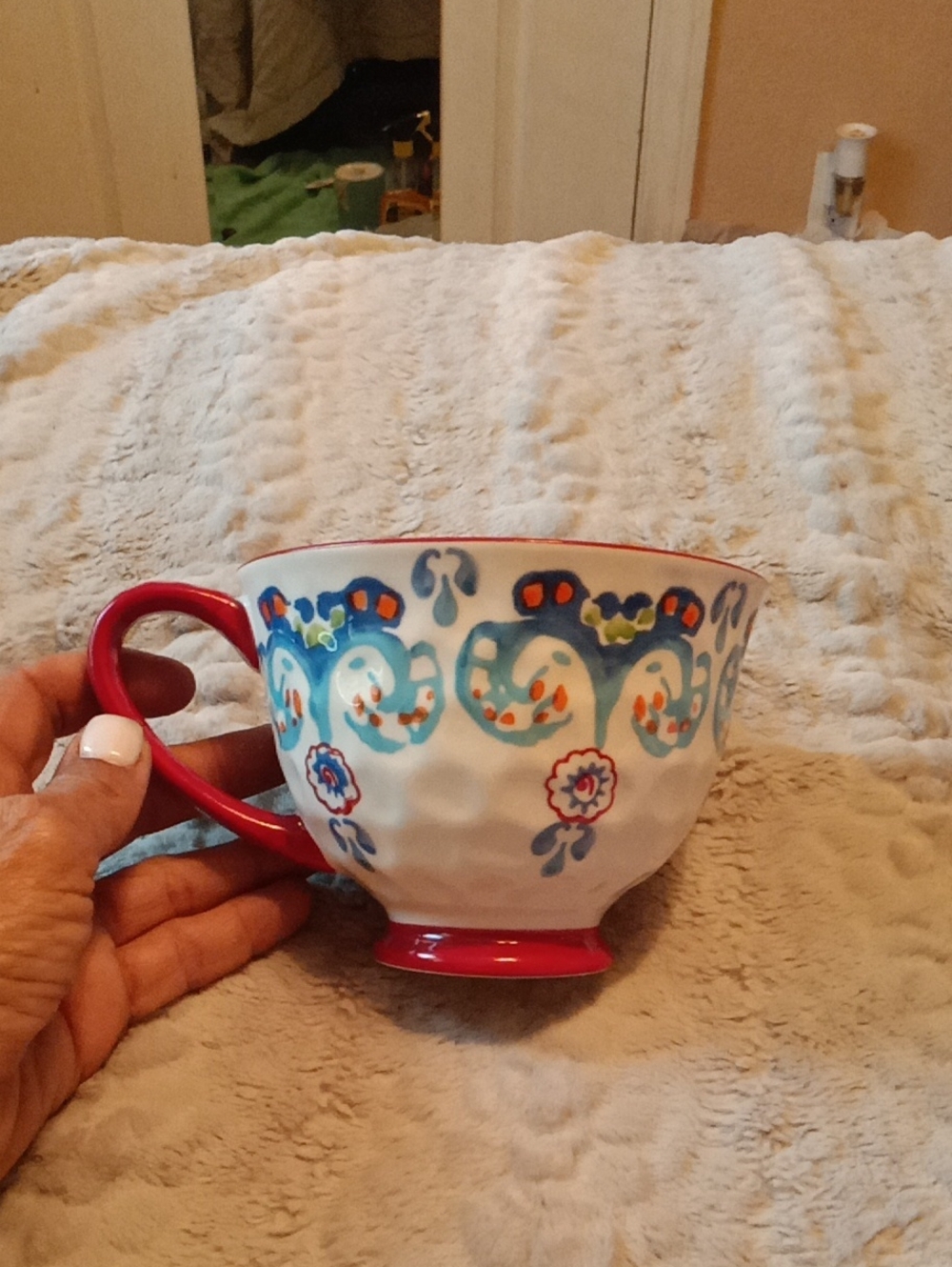 Decorative White Ceramic Teacup with Red Handle and Blue Floral Trim